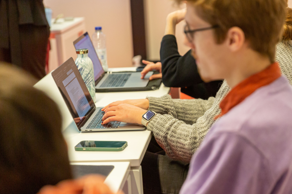 Students sitting around a table, each working or collaborating on their laptops